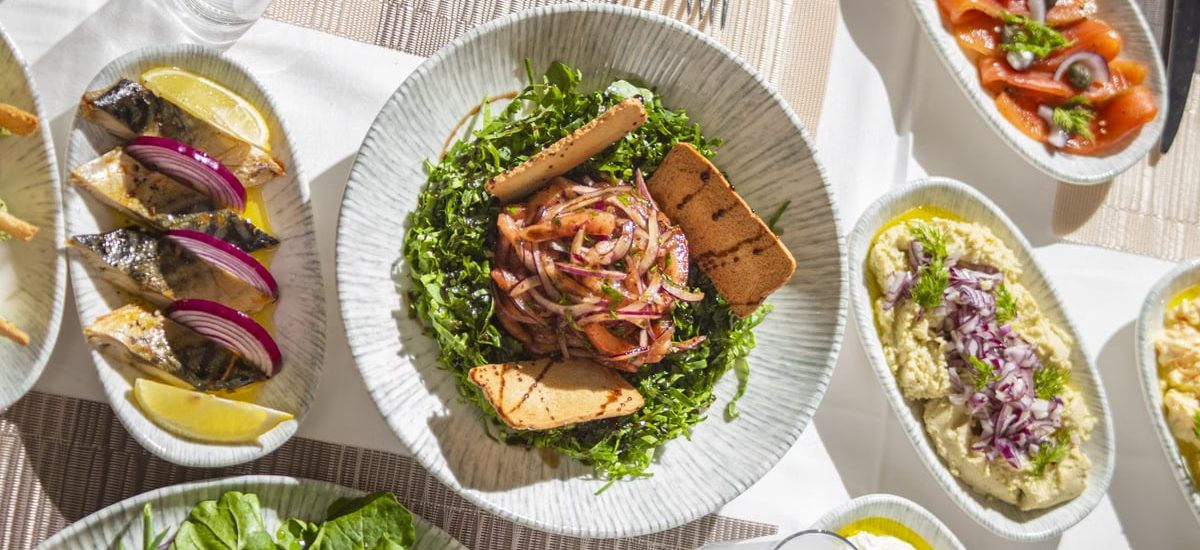 Top-down view of Mediterranean dishes including salads and seafood on an elegant table setting.