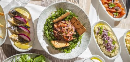 Top-down view of Mediterranean dishes including salads and seafood on an elegant table setting.