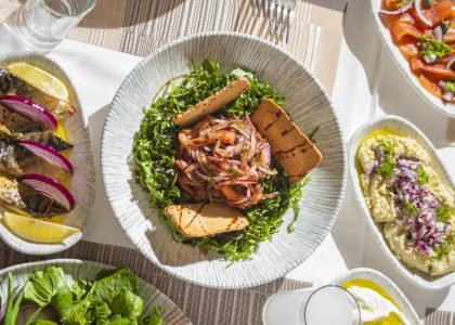 Top-down view of Mediterranean dishes including salads and seafood on an elegant table setting.
